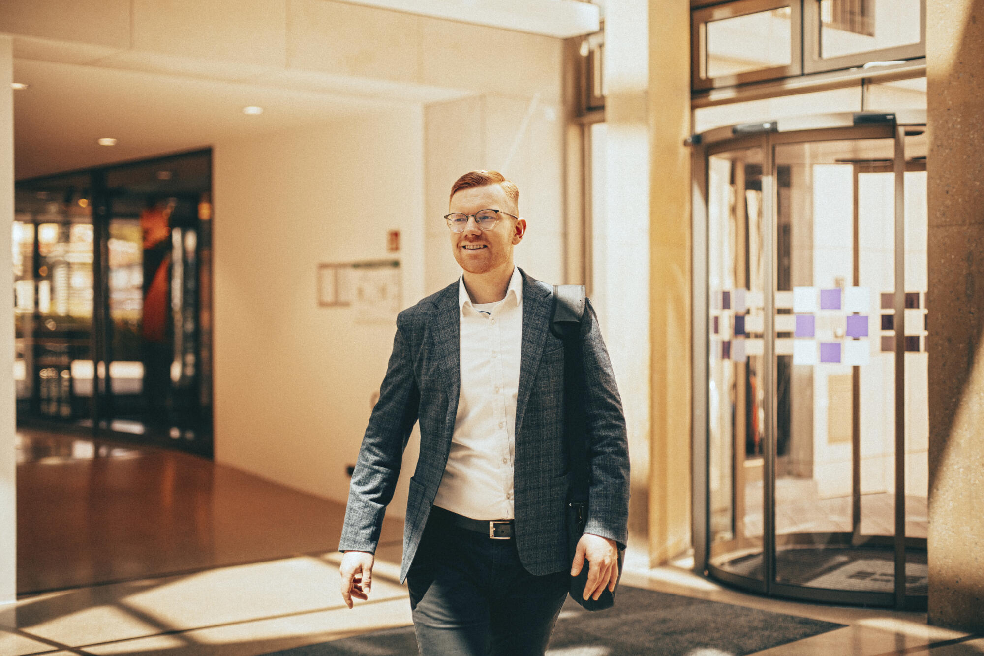 Carsten geht mit einer Tasche über der Schulter durch die Eingangshalle der Evangelischen Bank.