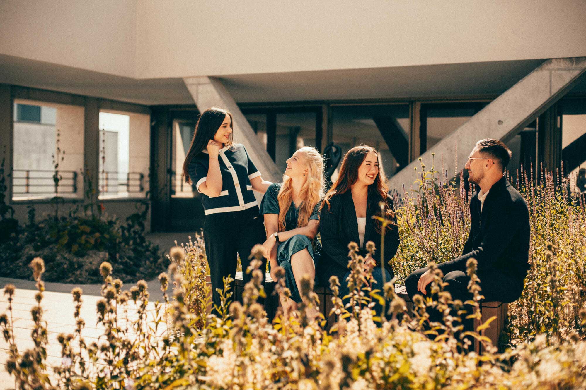 Gruppenbild von vier Auszubildenden der Evangelischen Bank, die sich unterhalten auf der begrünten Dachterrasse.