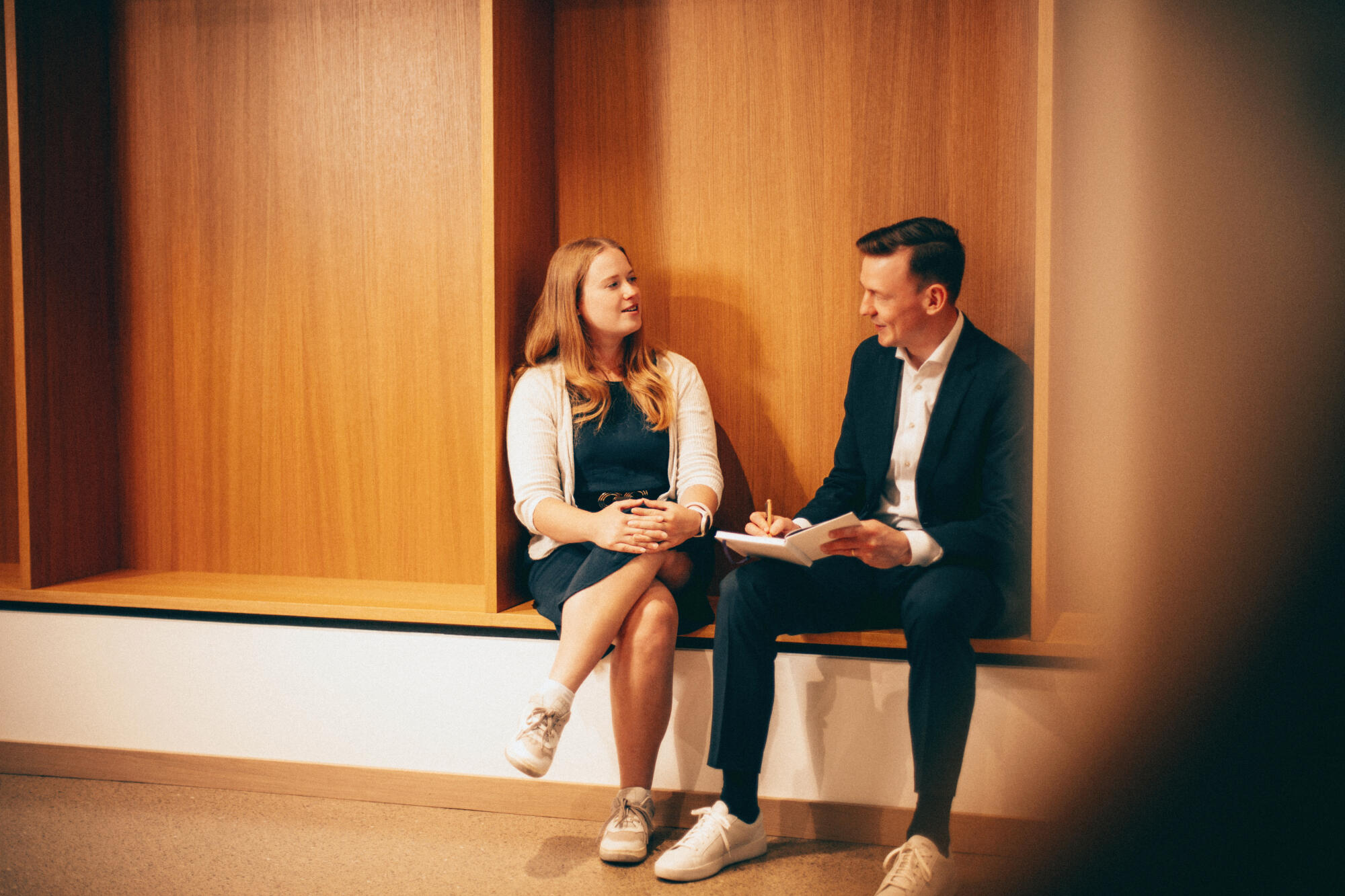 Zwei Mitarbeitende sitzen auf einer Bank und unterhalten sich.